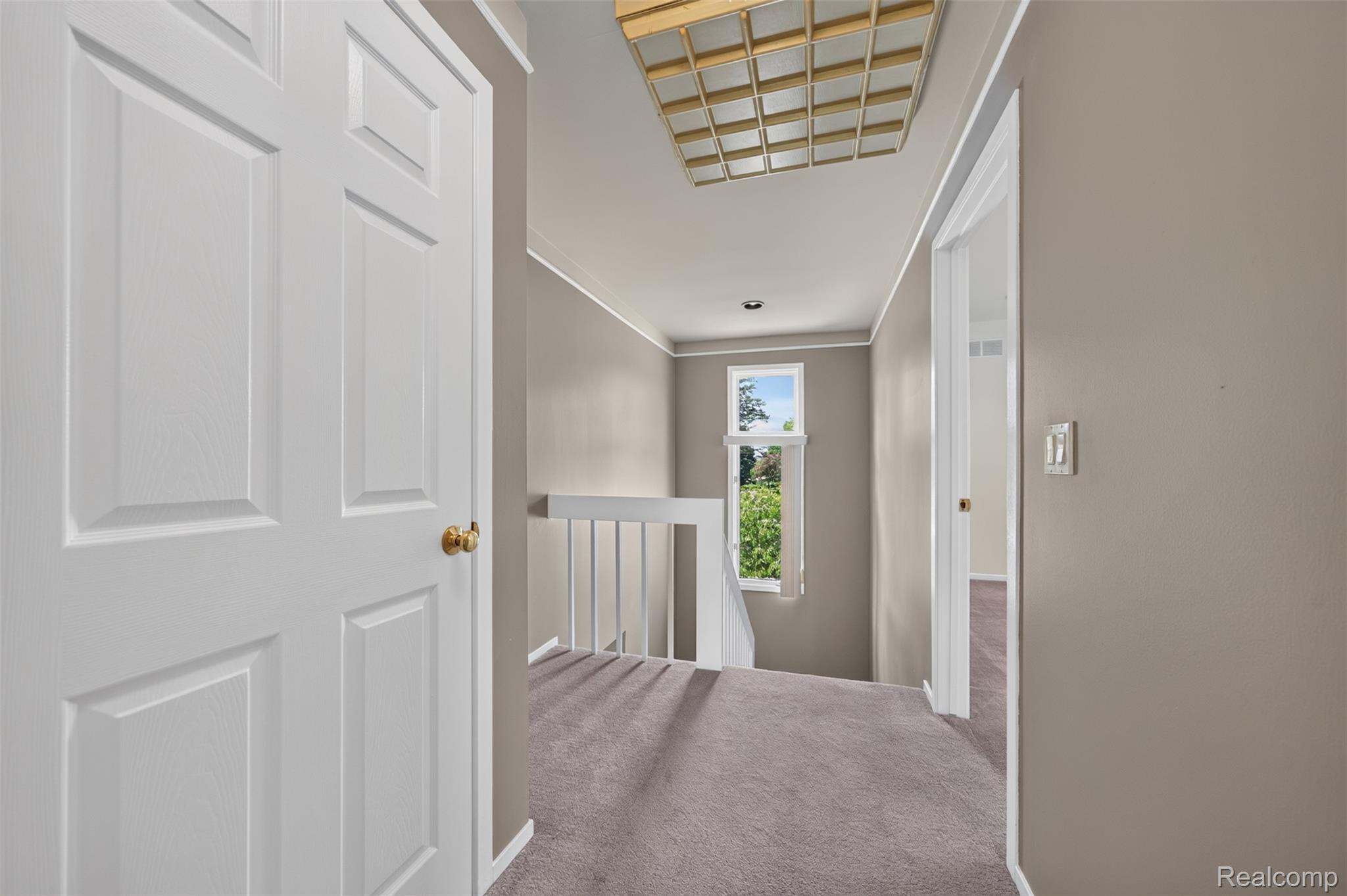 1236 Chaffer Drive Rochester, MI 48306 - Photo 41 of 76 Upper-level hallway featuring a window with exterior foliage, neutral wall tones, and carpet flooring
