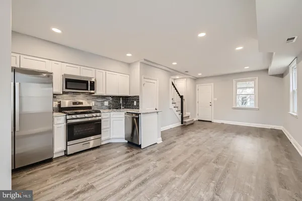 a kitchen with granite countertop a refrigerator and a stove top oven