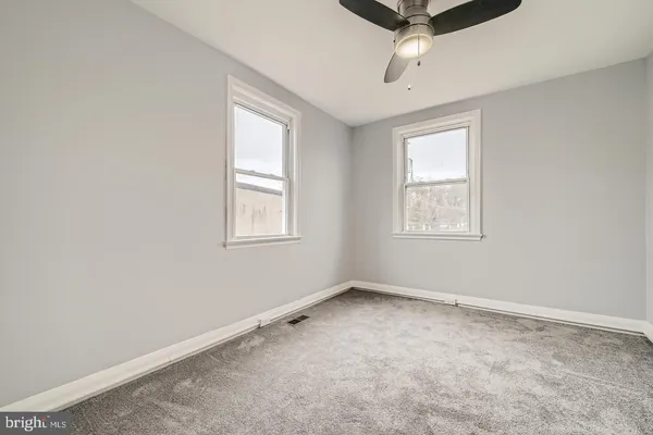 an empty room with windows and ceiling fan