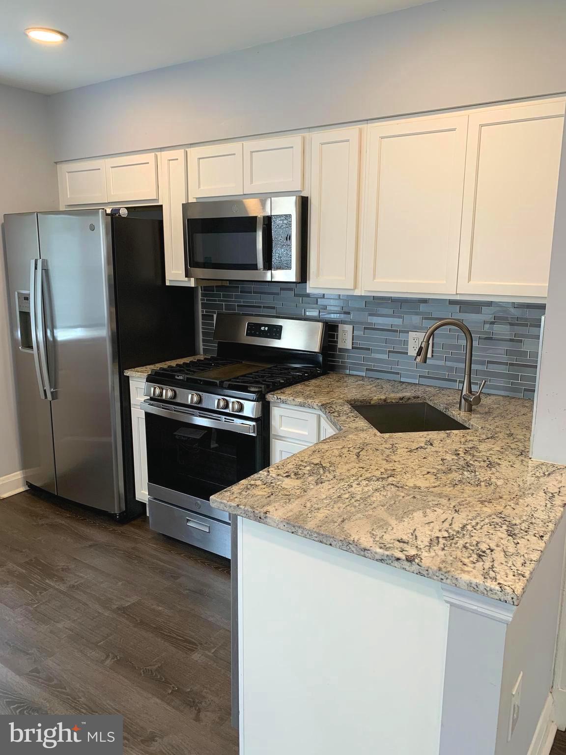 4429 Newport Avenue Baltimore, MD 21211 - Photo 4 of 17 a kitchen with a sink a microwave a stove and refrigerator