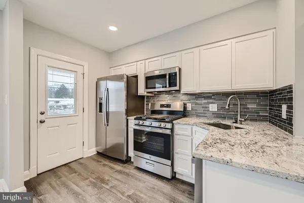 a kitchen with granite countertop a sink stove and refrigerator