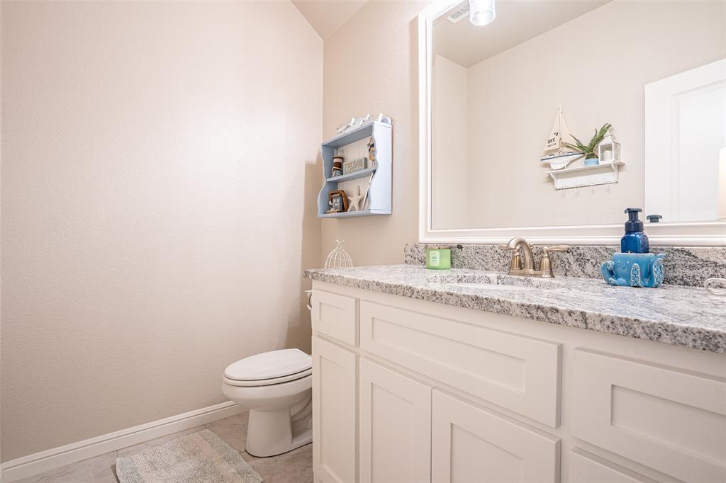 1920 Meander Road Granbury, TX 76049 - Photo 25 of 40 Bathroom vanity featuring a light-toned stone countertop, integrated sink, and brushed nickel faucet