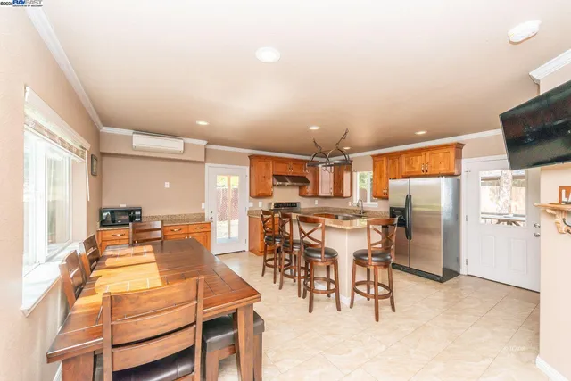a dining hall with stainless steel appliances kitchen island granite countertop a table and chairs