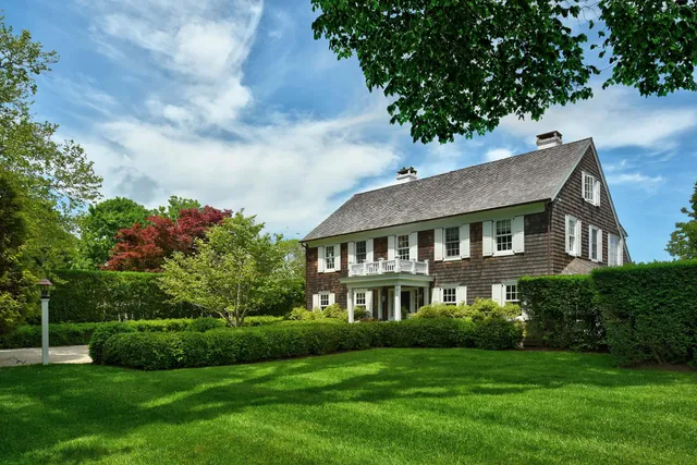a view of a house next to a big yard and large trees