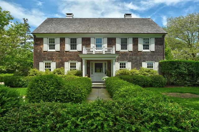 a view of a big house with a big yard plants and large trees