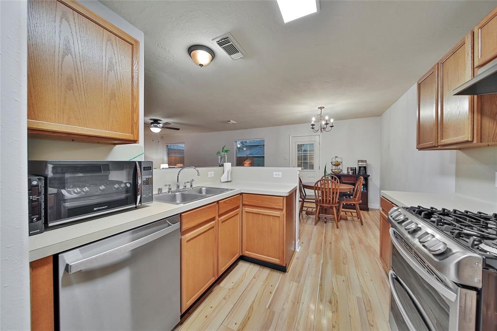 16923 Lockford Lane Houston, TX 77073 - Photo 4 of 7 a kitchen with stainless steel appliances granite countertop a stove top oven a sink dishwasher a dining table and chairs with wooden floor