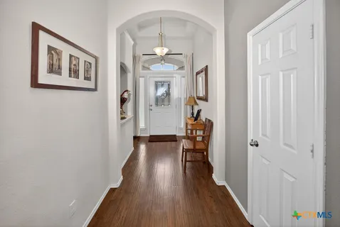 a view of a hallway with wooden floor and a livingroom