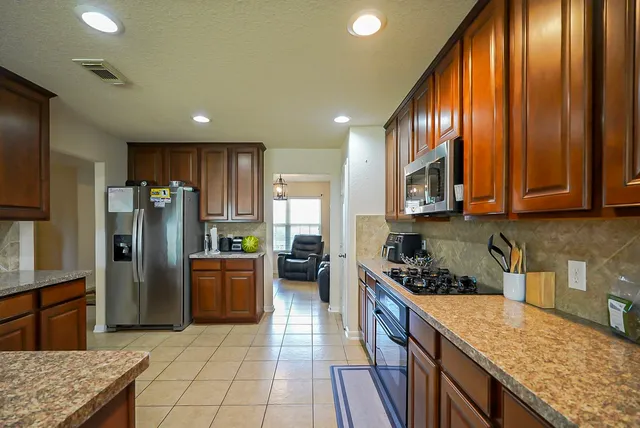 a kitchen with stainless steel appliances granite countertop a refrigerator stove and sink