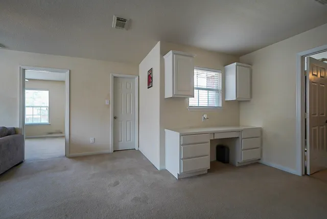 an empty room with windows and cabinet
