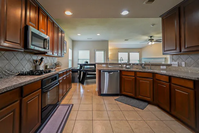 a kitchen with stainless steel appliances granite countertop wooden cabinets a stove top oven a sink and dishwasher