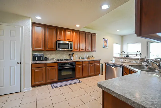 a large kitchen with granite countertop a stove sink and cabinets