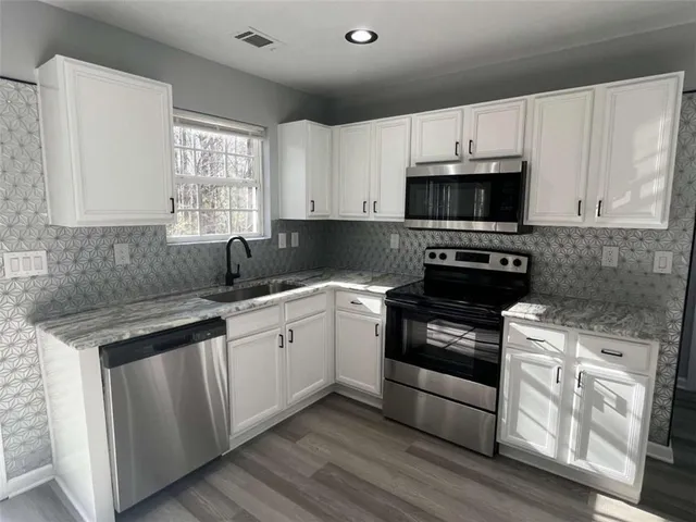 a kitchen with granite countertop a refrigerator and a stove top oven