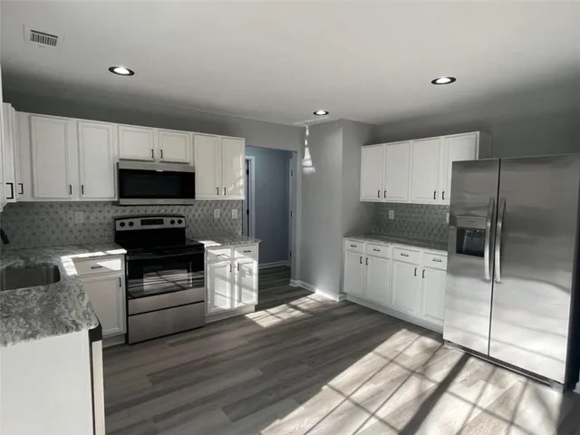 a view of an empty room with wooden floor and window