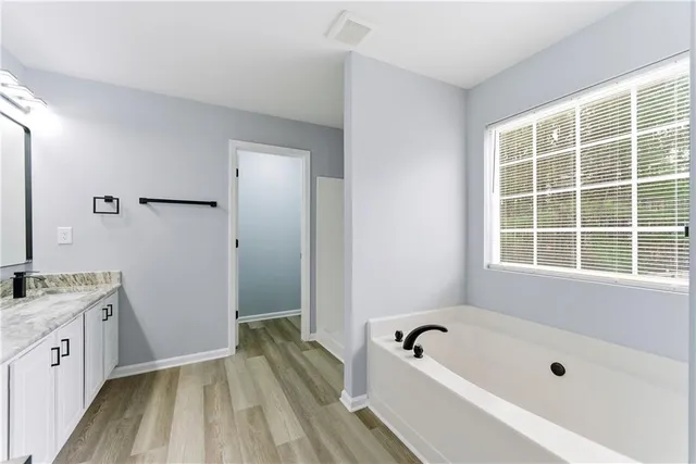 a bathroom with a tub a sink a window and a shower