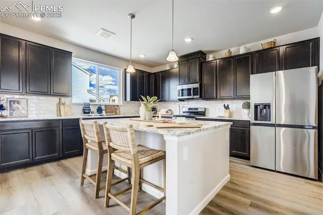 a kitchen with stainless steel appliances granite countertop a refrigerator a sink dishwasher a stove and white cabinets with wooden floor