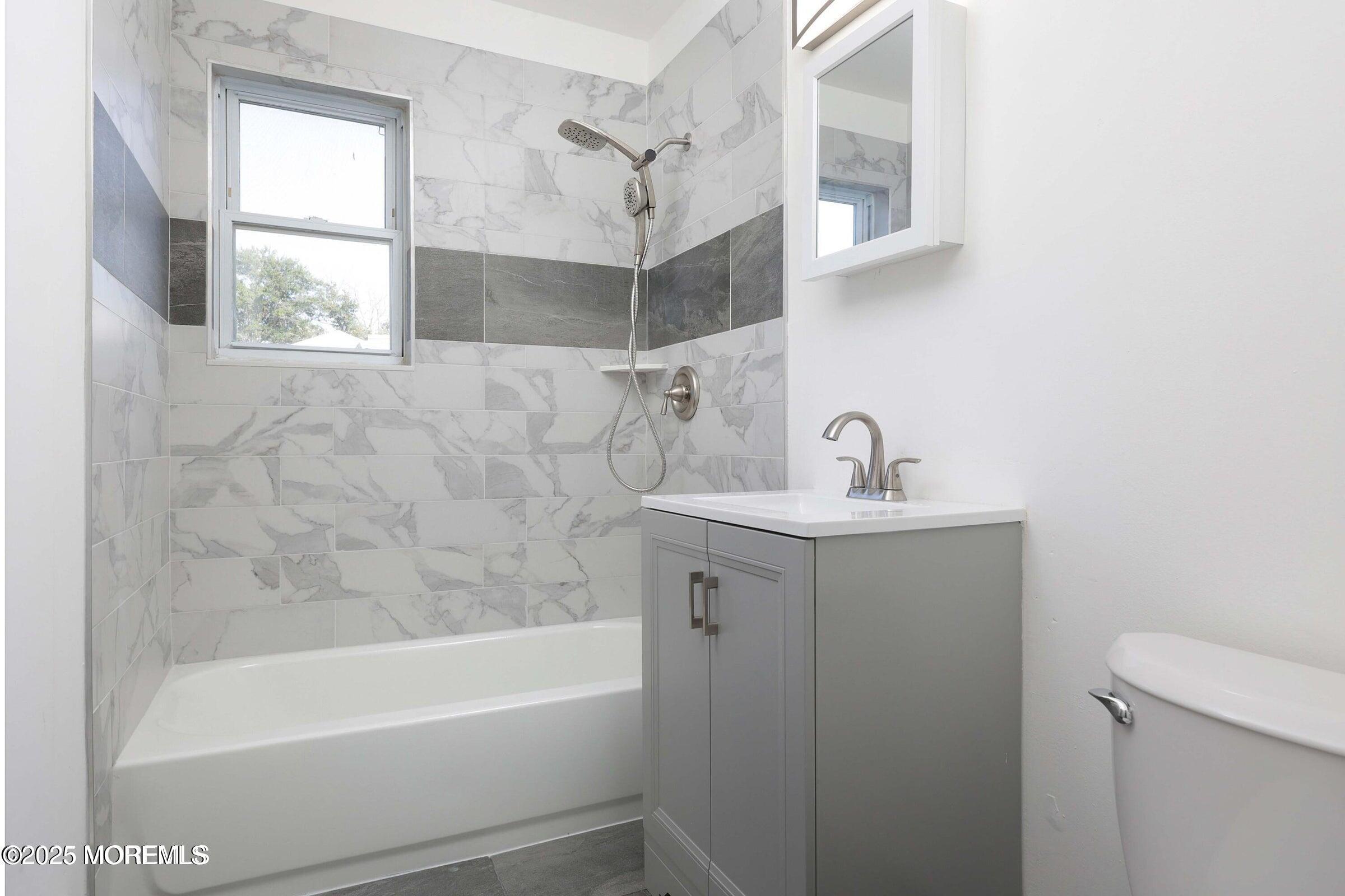 26 Windsor Terrace, Unit G Freehold, NJ 07728 - Photo 9 of 15 a bathroom with a sink a mirror and a bathtub