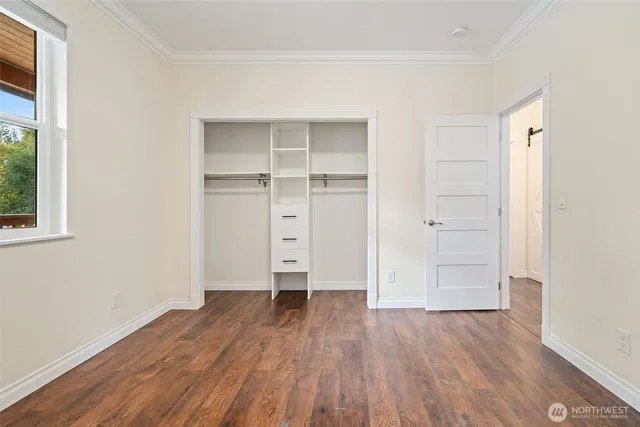 an empty room with wooden floor closet and windows