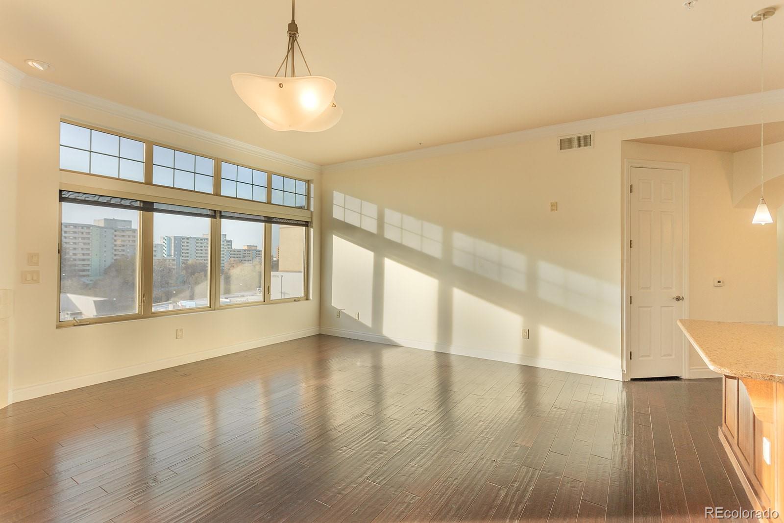 1120 Deleware, Unit 504 Denver, CO 80204 - Photo 4 of 29 a view of an empty room with wooden floor and a window