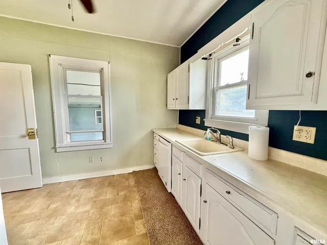 a large white kitchen with sink and window