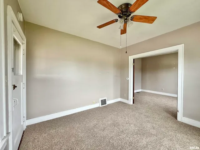 an empty room with windows and fan