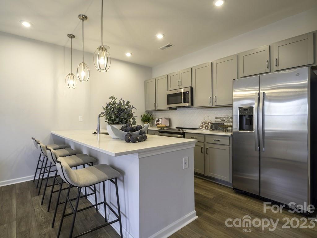 a kitchen with stainless steel appliances a dining table chairs refrigerator and microwave