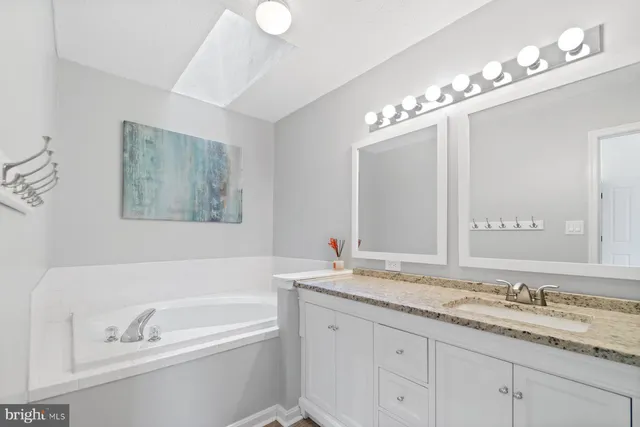 a bathroom with a granite countertop sink a large mirror and a bathtub