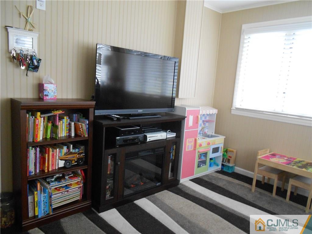 29 Kendall Road Kendall Park, NJ 08824 - Photo 9 of 22 a living room with a flat screen tv and a book shelf