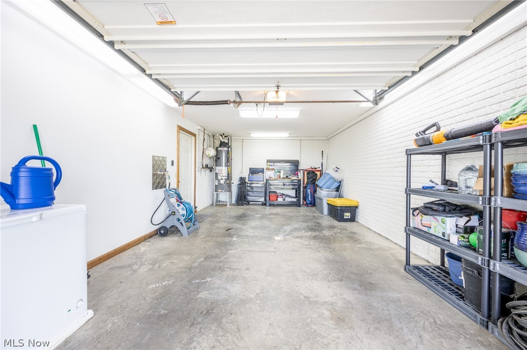 1602 Glendale Road, Unit 3 Marietta, OH 45750 - Photo 35 of 49 Spacious garage featuring a concrete floor, painted brick accent wall, utility door, and overhead lighting