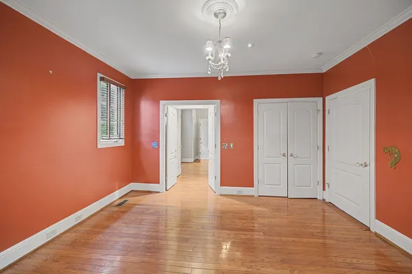 a view of an empty room with wooden floor and chandelier