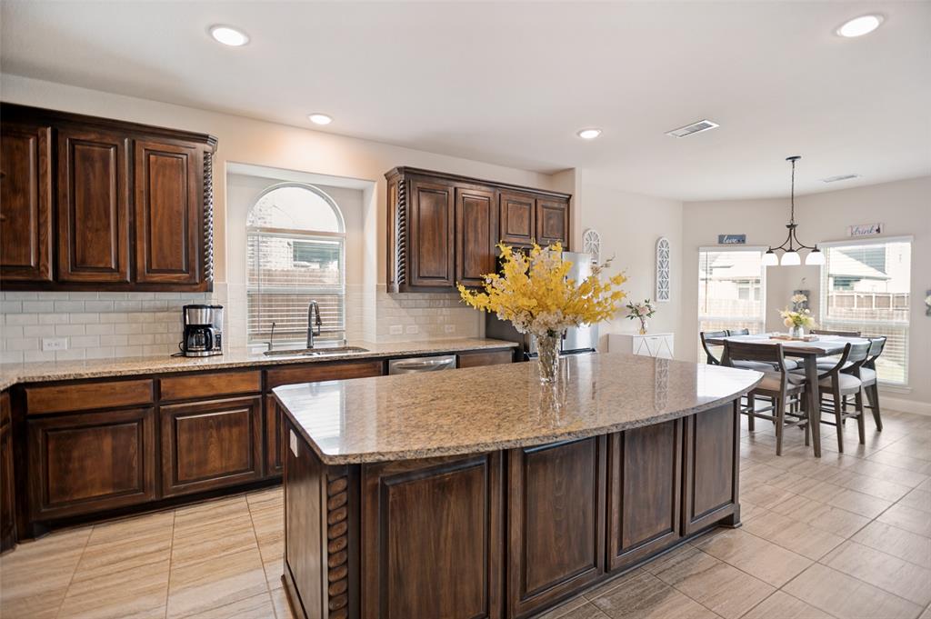 413 Frontier Court Midlothian, TX 76065 - Photo 8 of 26 Spacious kitchen featuring a large island with a stone countertop, dark wood cabinetry, subway tile backsplash, and recessed lighting