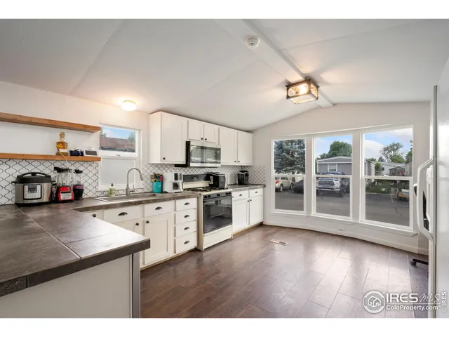 a kitchen with stainless steel appliances a stove a sink dishwasher a refrigerator and a microwave with wooden floor