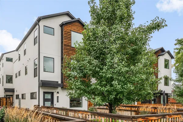 a view of a large building with a small yard and wooden fence