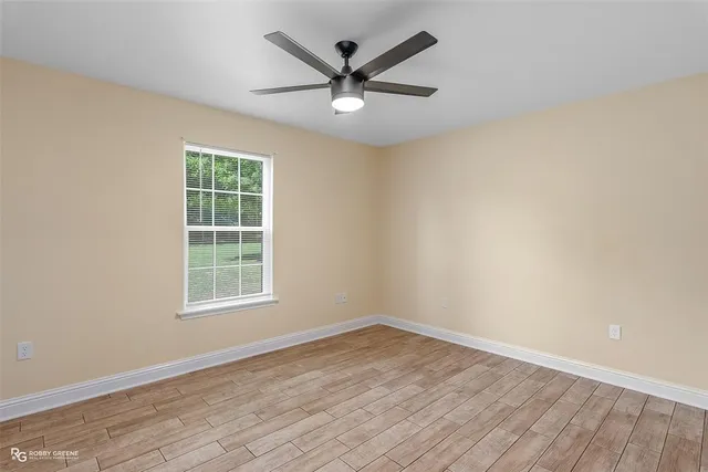 an empty room with wooden floor and ceiling fan