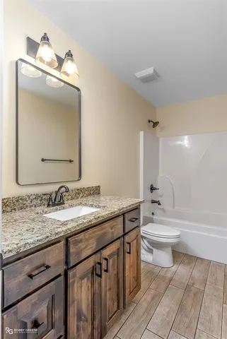 a bathroom with a granite countertop toilet sink and mirror