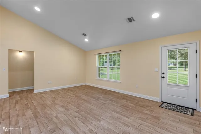 an empty room with wooden floor and windows