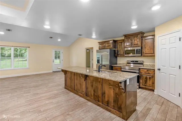 a large kitchen with stainless steel appliances granite countertop a stove and a wooden floors