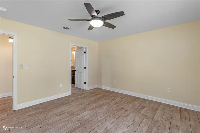 an empty room with wooden floor and a ceiling fan