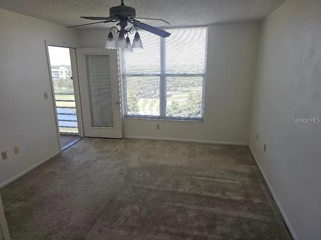 an empty room with windows and chandelier fan