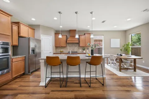 a kitchen with stainless steel appliances kitchen island granite countertop a refrigerator and chairs
