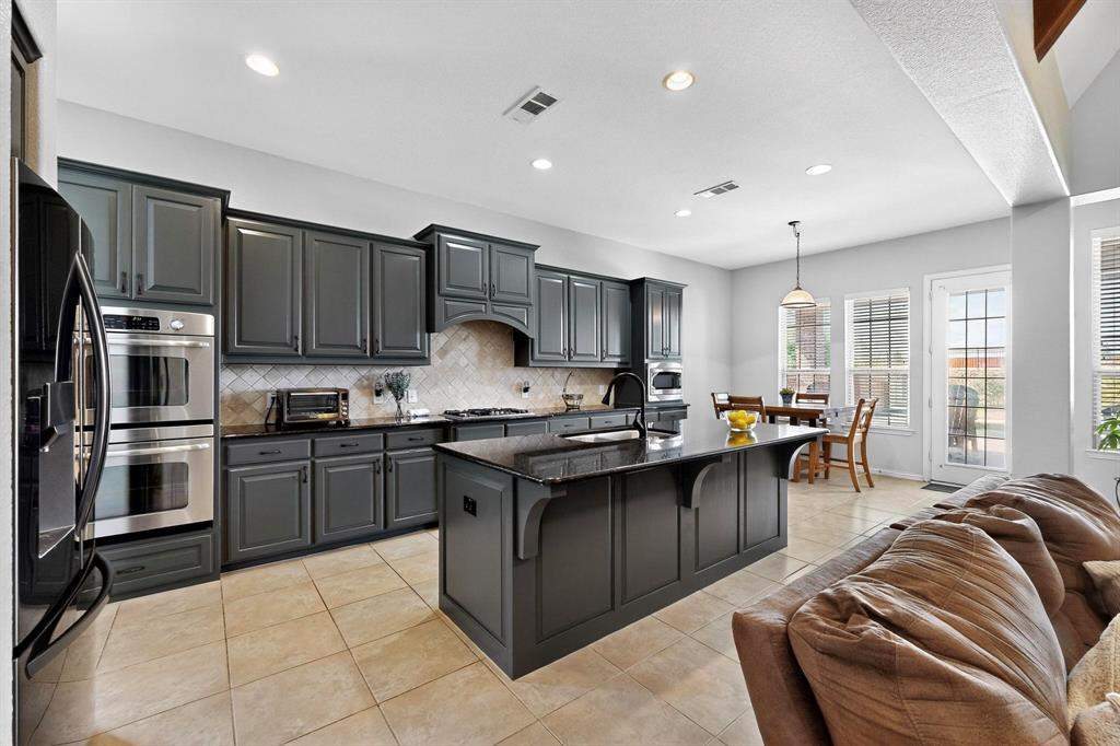 1240 Wedgewood Drive Forney, TX 75126 - Photo 13 of 40 a kitchen with stainless steel appliances granite countertop a stove top oven a sink dishwasher a dining table and chairs