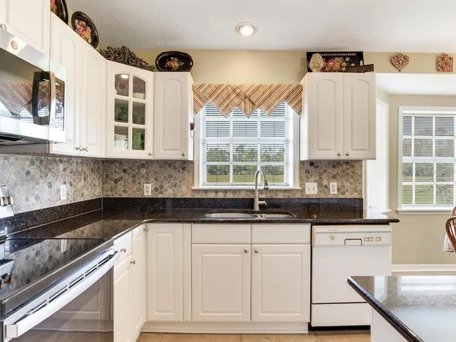 a kitchen with granite countertop white cabinets and white appliances