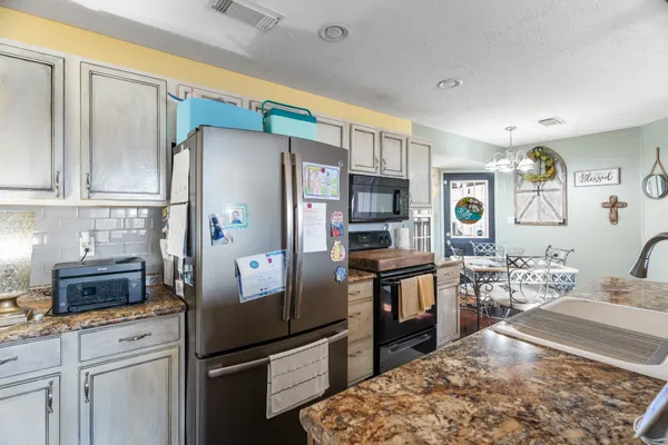 a kitchen with stainless steel appliances granite countertop a refrigerator stove and sink