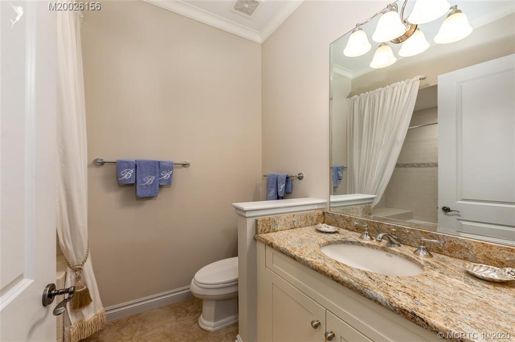982 Southeast Willoughby Trace, Unit 15 Stuart, FL 34997 - Photo 18 of 36 a bathroom with a granite countertop sink a toilet and a mirror