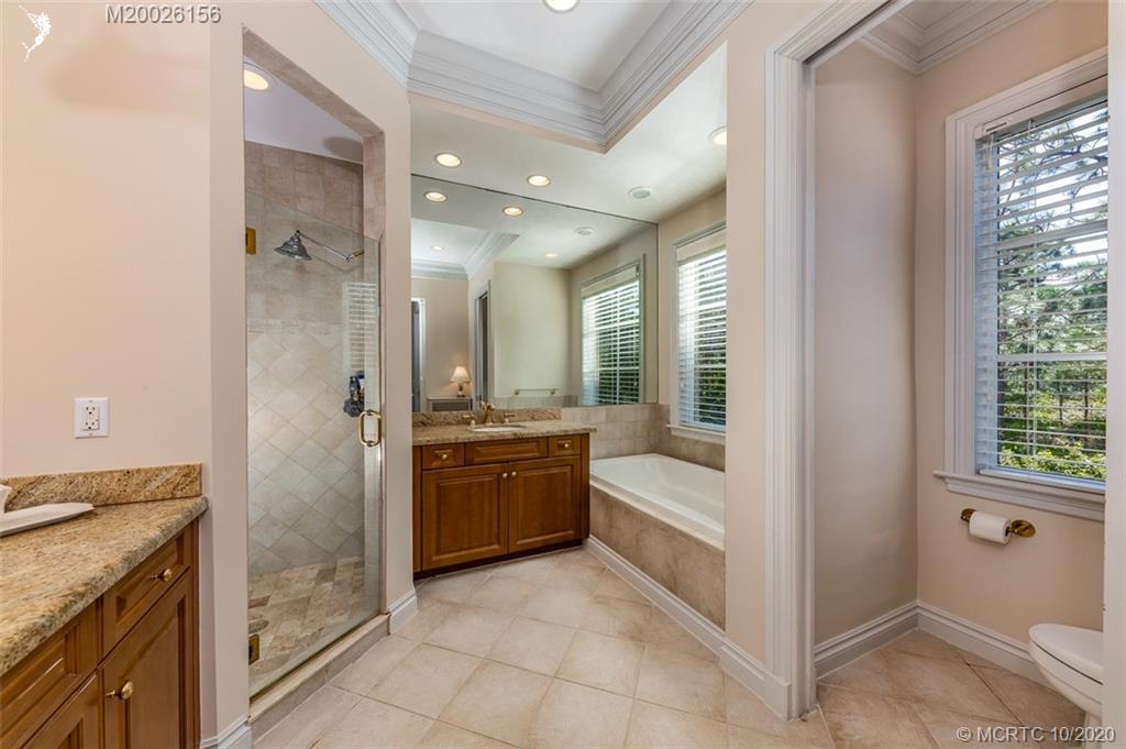 982 Southeast Willoughby Trace, Unit 15 Stuart, FL 34997 - Photo 21 of 36 a bathroom with a granite countertop sink a mirror and a bathtub