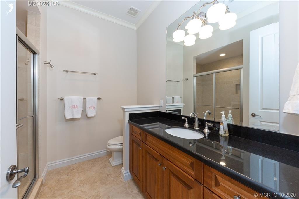 982 Southeast Willoughby Trace, Unit 15 Stuart, FL 34997 - Photo 23 of 36 a bathroom with a granite countertop sink a toilet and mirror