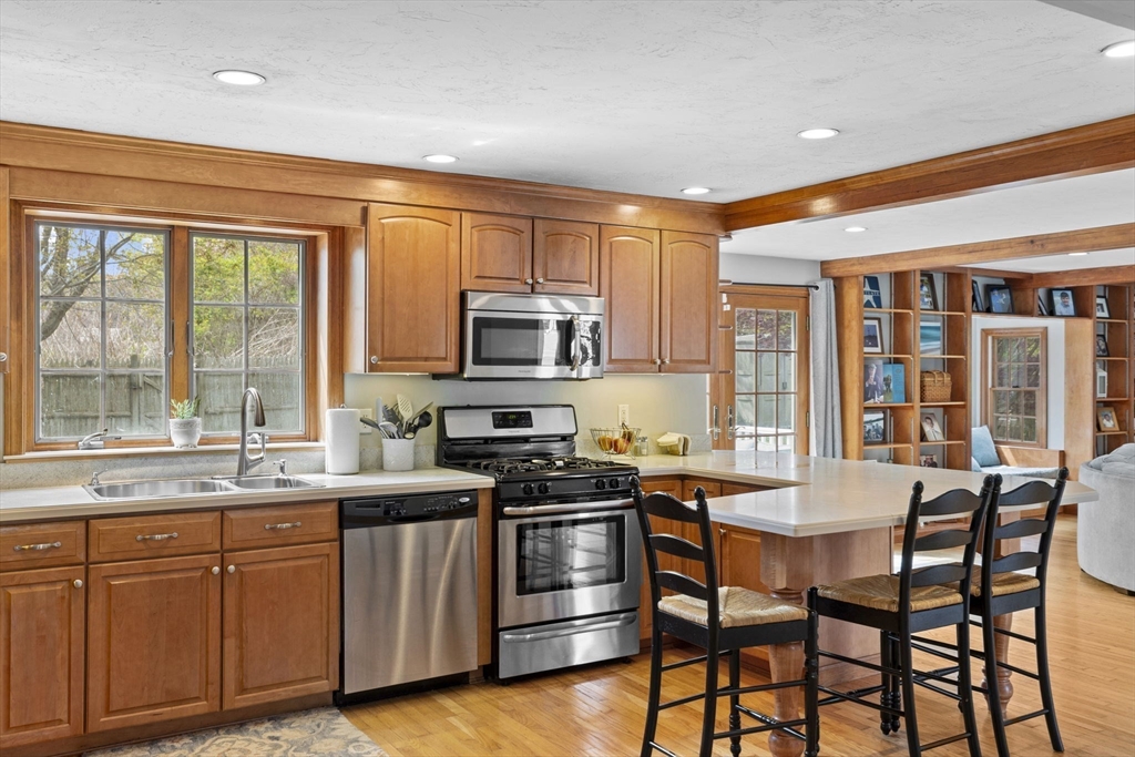 3 Marion Road Scituate, MA 02066 - Photo 9 of 30 a kitchen with stainless steel appliances granite countertop a stove top oven a sink dishwasher a dining table and chairs with wooden floor