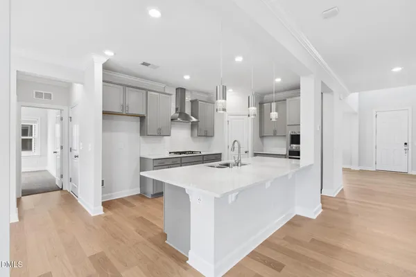 a large kitchen with stainless steel appliances kitchen island wooden floors and white cabinets