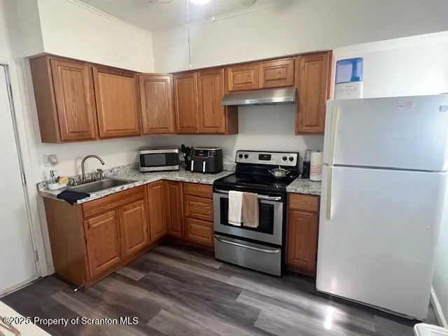 a kitchen with stainless steel appliances granite countertop a refrigerator a stove and a sink with wooden floor