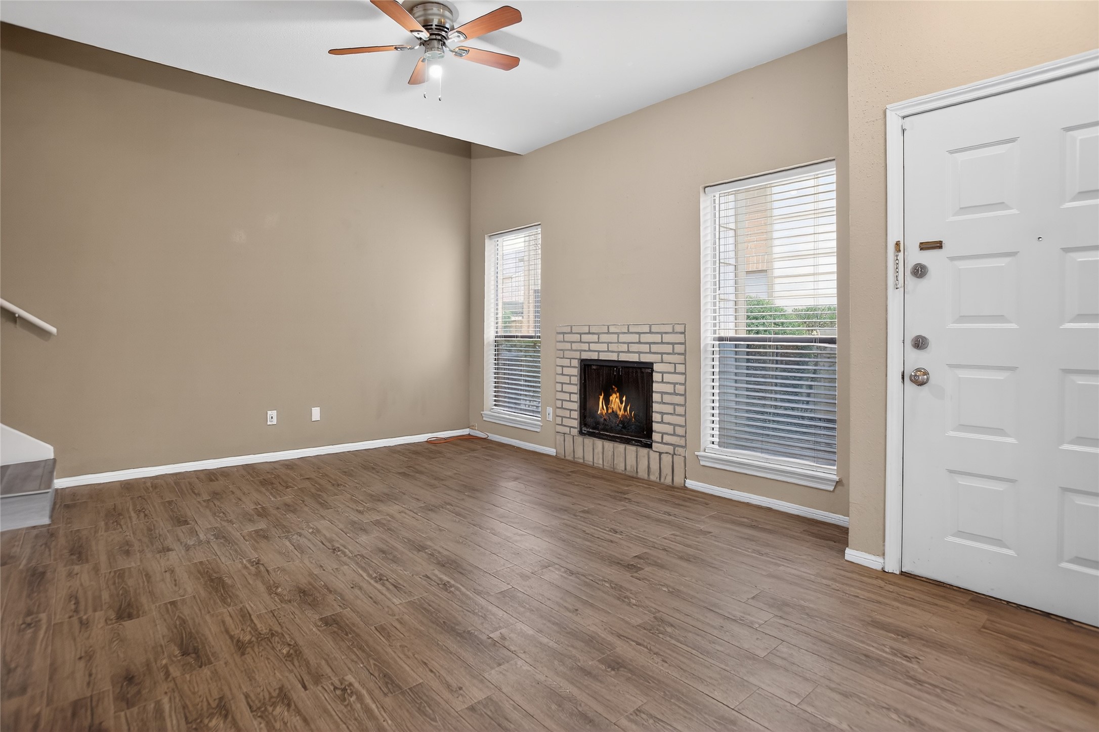 8299 Cambridge Street, Unit 706 Houston, TX 77054 - Photo 4 of 30 an empty room with wooden floor a fireplace a ceiling fan and windows