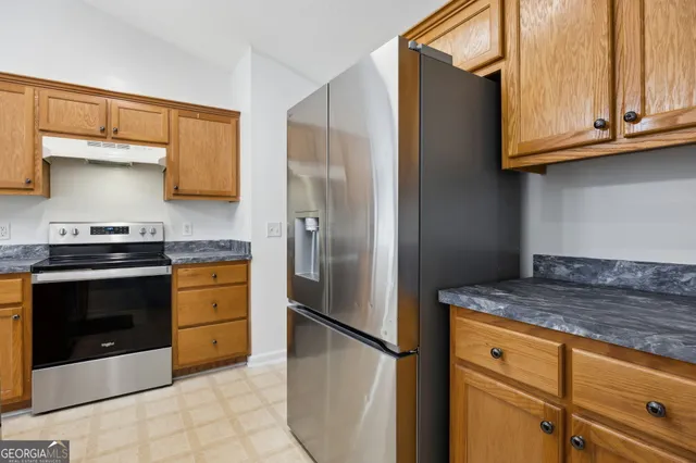 a kitchen with stainless steel appliances granite countertop a refrigerator stove and cabinets